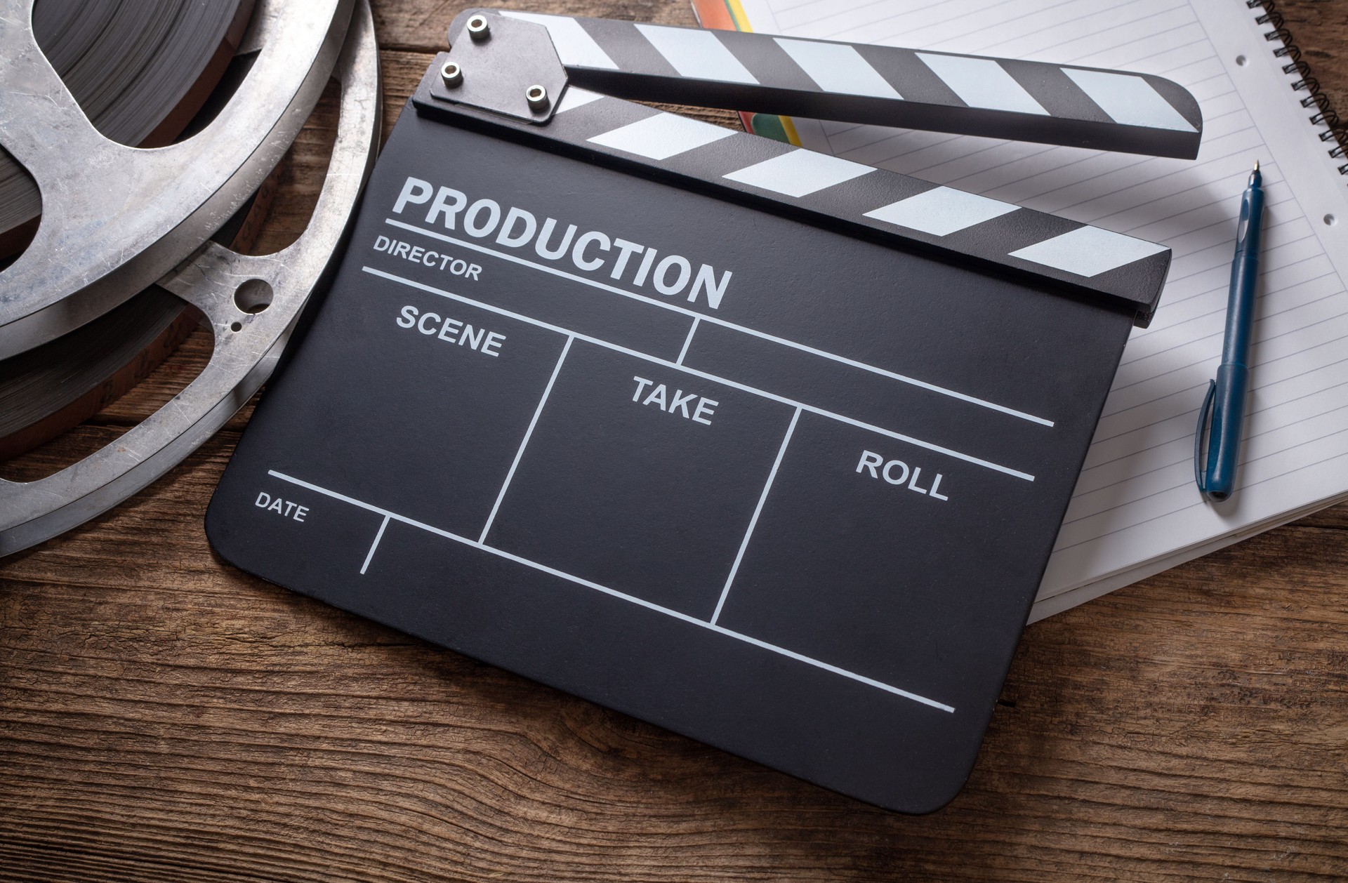 Movie clapper and film reel on wooden background